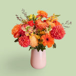 Orange flowers vase arrangement in pink vase