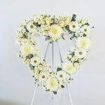 Heart-shaped floral arrangement on a stand against a white background