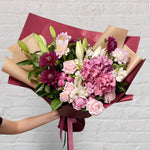 Crimson bouquet featuring red tones of flowers - lilies, roses, dahlias, alstromerias.