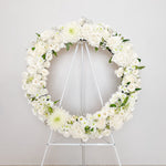 white flowers round wreath with stand
