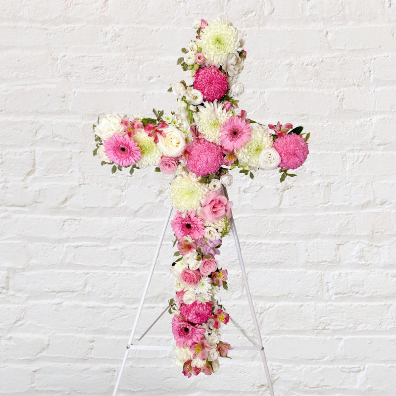 Baby pink and white flowers cross wreath on white stand