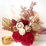 A mix of preserved flowers and silk flowers of hydrangea, Italian ruscus, silk flower, fox tail, palm arranged in a in white vase.