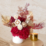 A mix of preserved flowers and silk flowers of hydrangea, Italian ruscus, silk flower, fox tail, palm arranged in a in white vase.