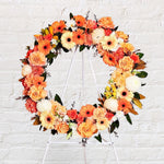 Orange Round Wreath featuring seasonal flowers - gerberas, dahlias, spray roses, roses, tiger lily, snap dragon, chrysanthemum, greenery.