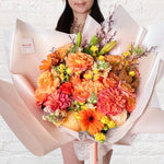 orange bouquet featuring orange and yellow tones of flowers - roses, dahlias, spray roses, snap dragon, lilies, gerberas & greenery.