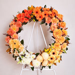 Two toned orange, yellow and white flowers round wreath featuring seasonal flowers - roses, gerberas, dahlias, chrysanthemums, tiger lilies, princess lily, greenery