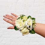 classic white corsage featuring roses, greenery, baby's breath, satin ribbon. Perfect for prom and weddings.