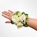 classic white corsage featuring roses, greenery, baby's breath, satin ribbon. Perfect for prom and weddings.