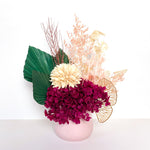 A mix of preserved flowers and silk flowers of hydrangea, magnolia flower, cherry blossom, honesty, nigella, cloudy leaf, misty and palm in a in white vase.