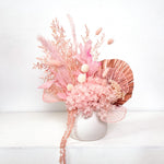 A mix of preserved flowers and silk flowers of hydrangea, ruscus, amaranthus, billy button, bunny tails, peony flower, rice flower, palm and fluffy stick in a in white vase.