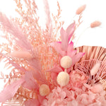 A mix of preserved flowers and silk flowers of hydrangea, ruscus, amaranthus, billy button, bunny tails, peony flower, rice flower, palm and fluffy stick in a in white vase.