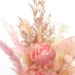 A mix of preserved flowers and silk flowers of hydrangea, Italian ruscus, bunny tails, baby's breath, rice flower, peony flower, palm and fluffy stick in a in white vase.