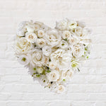 white filled heart wreath featuring seasonal flowers - roses, spray roses, chrysanthemum.