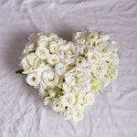 white filled heart wreath featuring seasonal flowers - roses, spray roses, chrysanthemum.