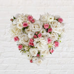 white filled heart wreath featuring seasonal flowers - roses, spray roses, chrysanthemum.