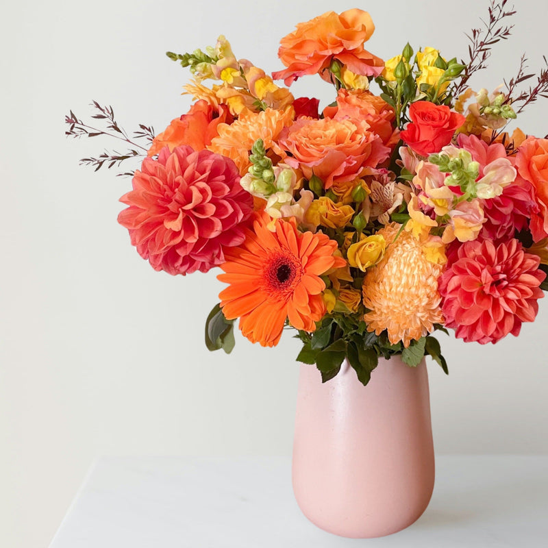 Orange flowers vase arrangement in pink vase