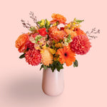Orange flowers vase arrangement in pink vase