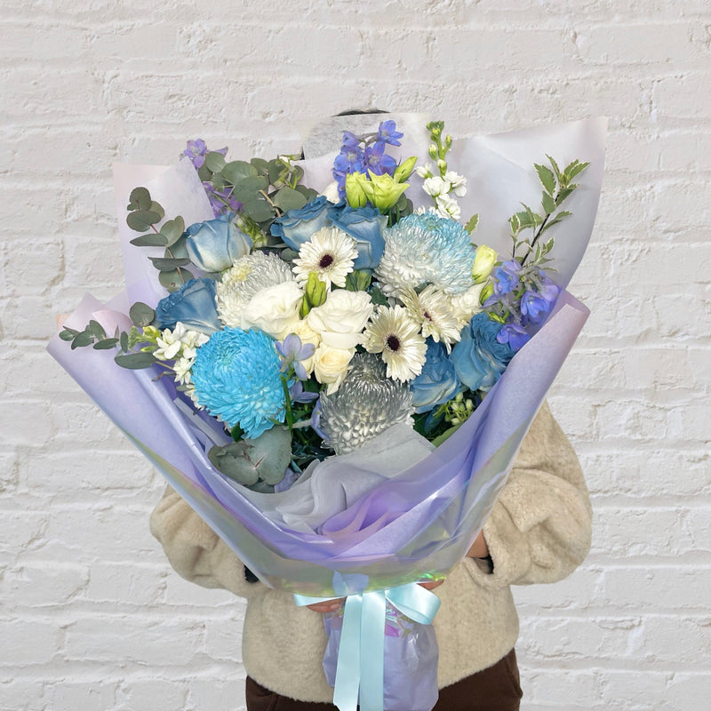 blue bouquet featuring blue and white flowers - roses, chrysanthemum, Delphinium,  gerberas, lisianthus, eucalyptus. 