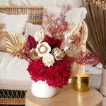 A mix of preserved flowers and silk flowers of hydrangea, Italian ruscus, silk flower, fox tail, palm arranged in a in white vase. 