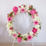 Baby pink and white flowers round wreath with white stand