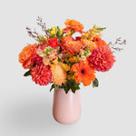 Orange flowers vase arrangement in pink vase