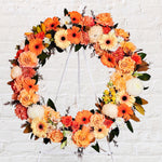 Orange Round Wreath featuring seasonal flowers - gerberas, dahlias, spray roses, roses, tiger lily, snap dragon, chrysanthemum, greenery. 