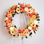 Orange Round Wreath featuring seasonal flowers - gerberas, dahlias, spray roses, roses, tiger lily, snap dragon, chrysanthemum, greenery. 