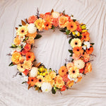 Orange Round Wreath featuring seasonal flowers - gerberas, dahlias, spray roses, roses, tiger lily, snap dragon, chrysanthemum, greenery. 