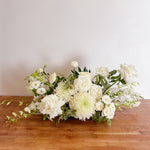 white & greens table centerpiece featuring seasonal flowers - roses, disbuds, Singapore orchid, spray roses, greenery, snap dragons. 