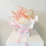 A mix of preserved flowers and silk flowers of hydrangea, Italian ruscus, gingko, baby's breath, rice flower, and peony flower arranged in a in pink vase. 